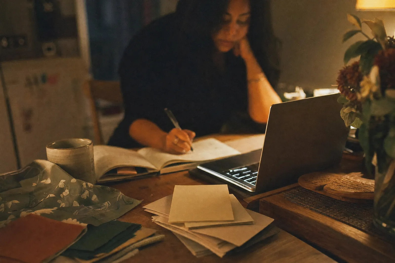 An organizer planning an event at a kitchen table late in the evening