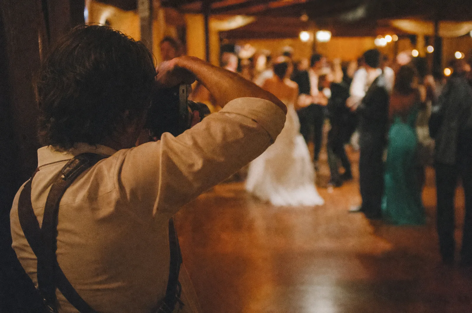 A wedding photographer working the reception from the edge of the dancefloor